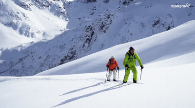 a couple of people riding skis down a snow covered slope