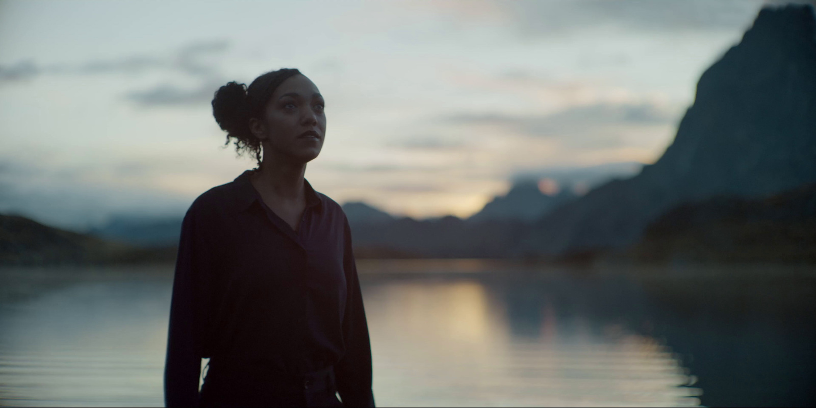 a woman standing in front of a body of water