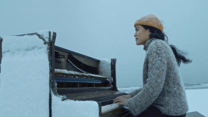 a woman playing a piano in the snow