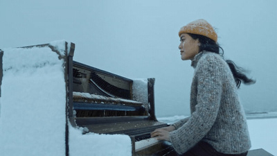 a woman playing a piano in the snow