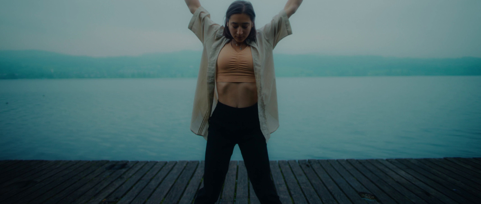 a woman is standing on a dock with her arms outstretched