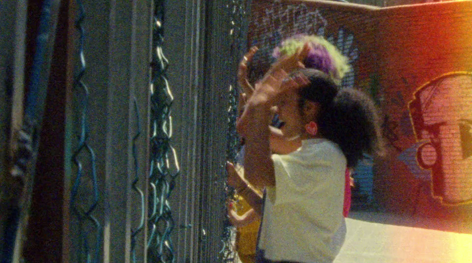 a little girl standing next to a chain link fence