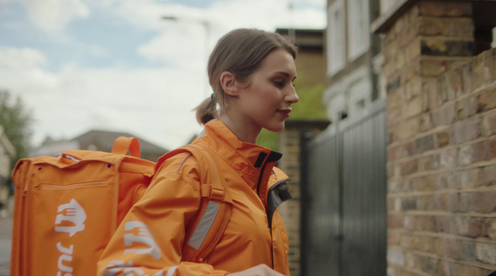 a woman in an orange jacket carrying a backpack