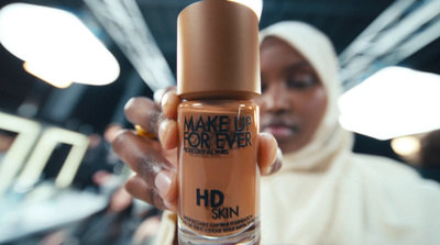 a woman holding up a bottle of makeup