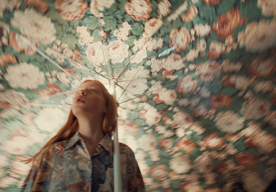 a woman standing under an umbrella with her eyes closed