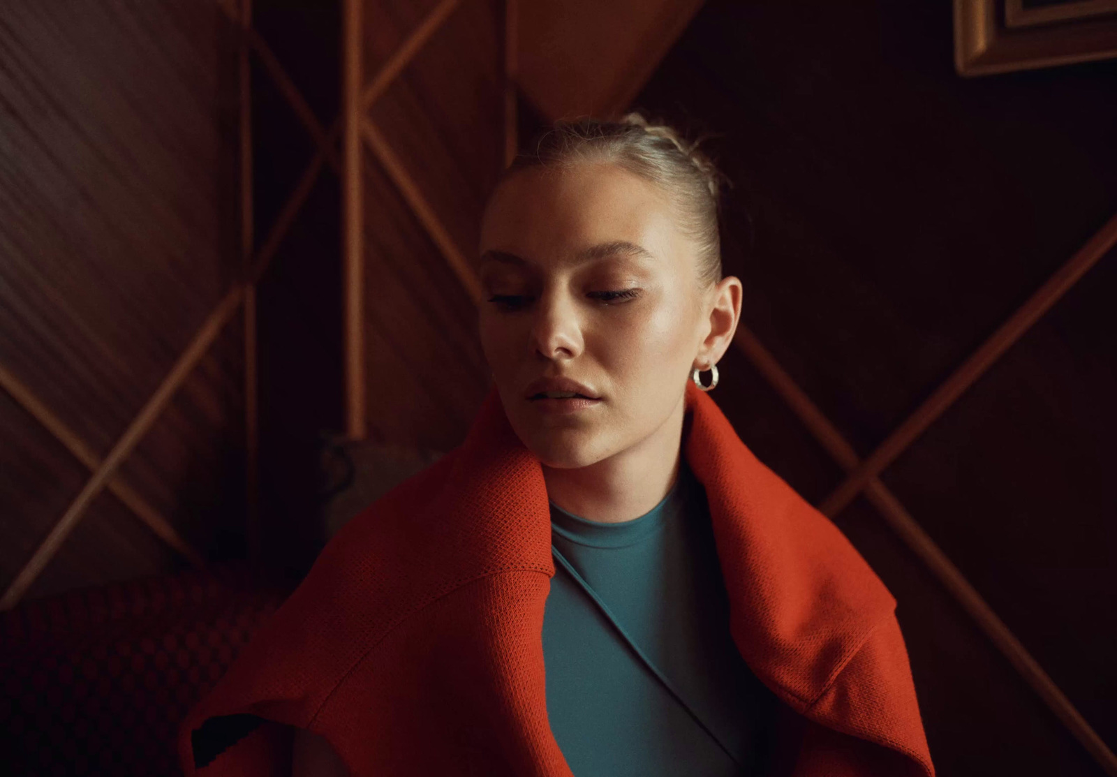 a woman wearing a red jacket and earrings