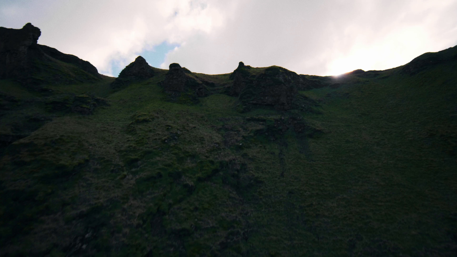 a view of a grassy hill with a sky in the background