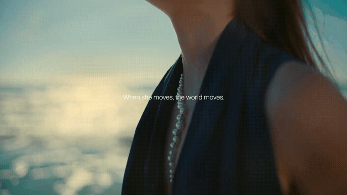 a woman with a pearl necklace looking at the ocean