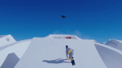 a man riding a snowboard down the side of a snow covered slope