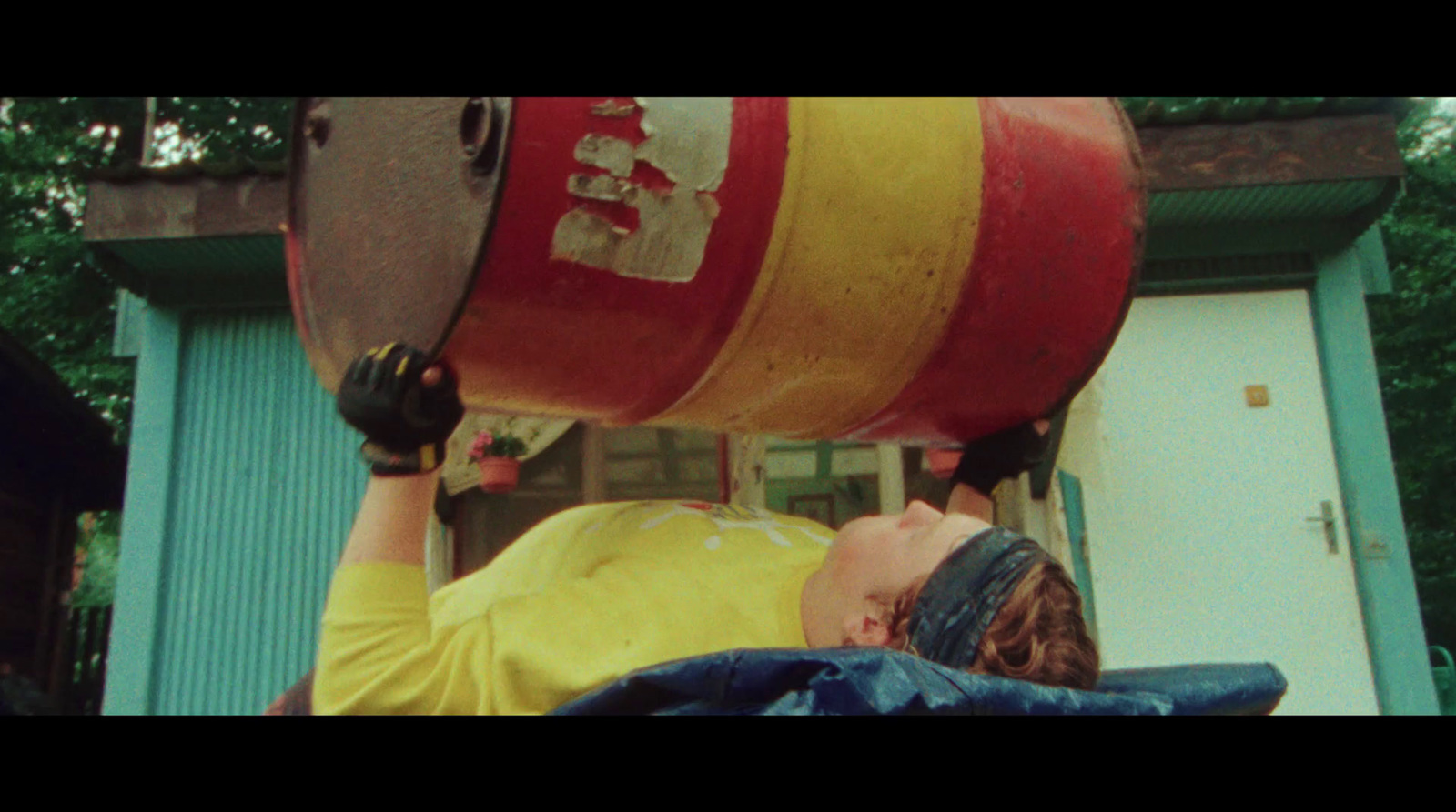 a man in a yellow shirt is holding a barrel