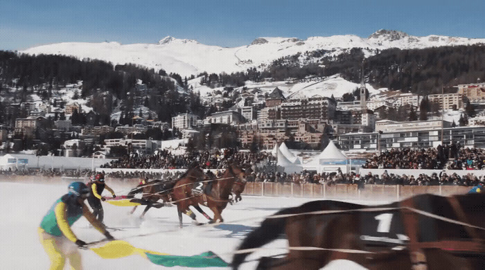 a group of people riding horses on top of a snow covered field