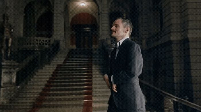 a man in a suit standing in front of a staircase