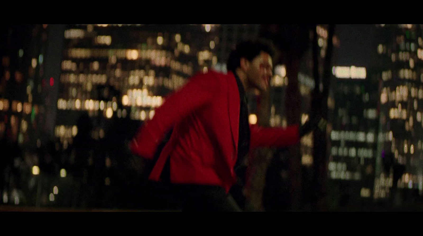 a man in a red jacket is running in the city at night