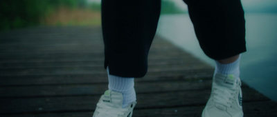 a person standing on a dock wearing white sneakers and socks