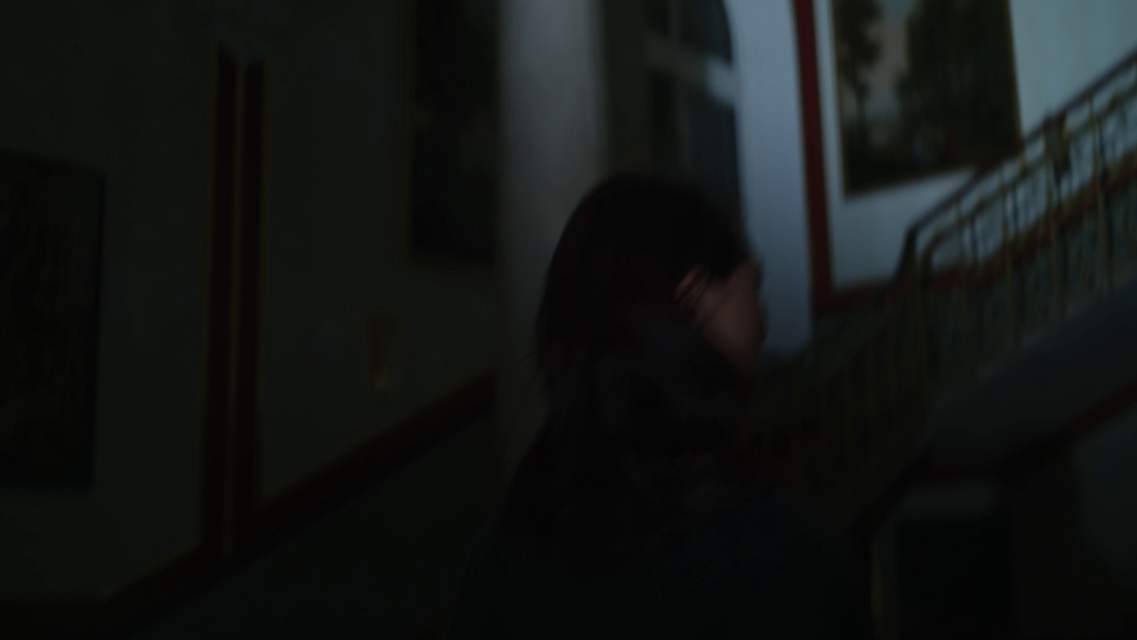 a woman walking down a hallway in the dark