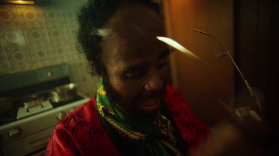 a man in a red shirt and green scarf in a kitchen