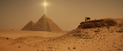 two people standing on a rock in front of two pyramids