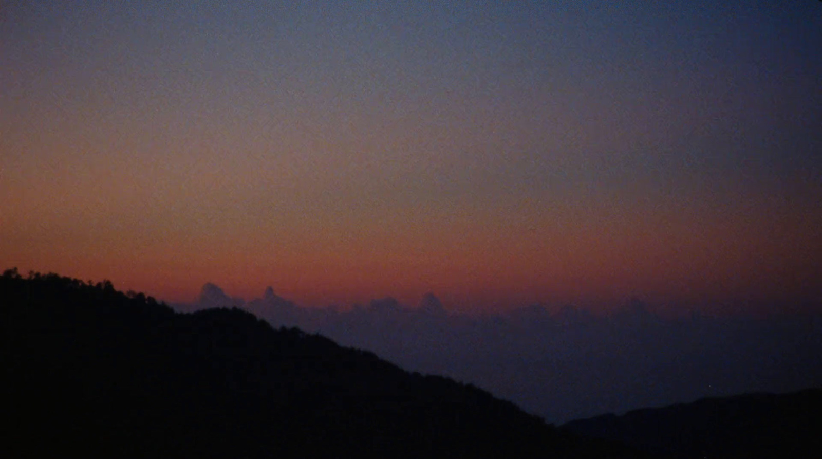 a plane flying over a mountain at sunset