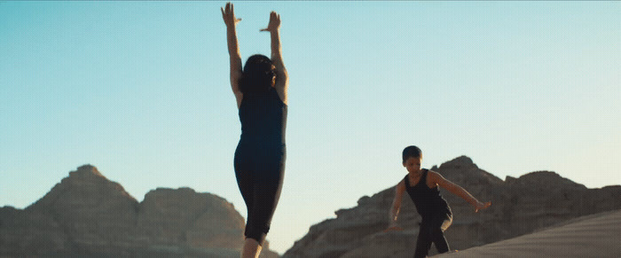 two people are playing with a frisbee in the desert