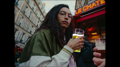 a woman holding a glass of beer in front of a building