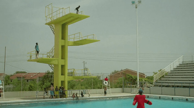 a group of people standing around a swimming pool