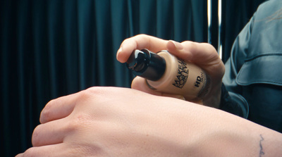 a person with a tattoo on their arm holding a bottle of nail polish