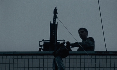 a man standing on top of a roof next to a power pole