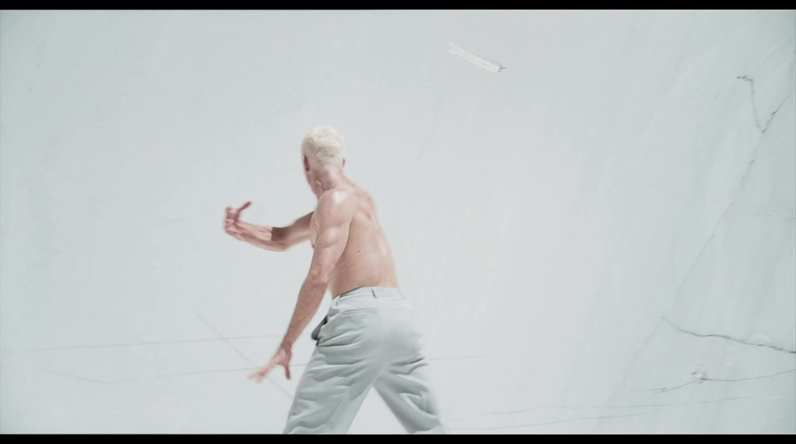 a shirtless man throwing a frisbee in the air