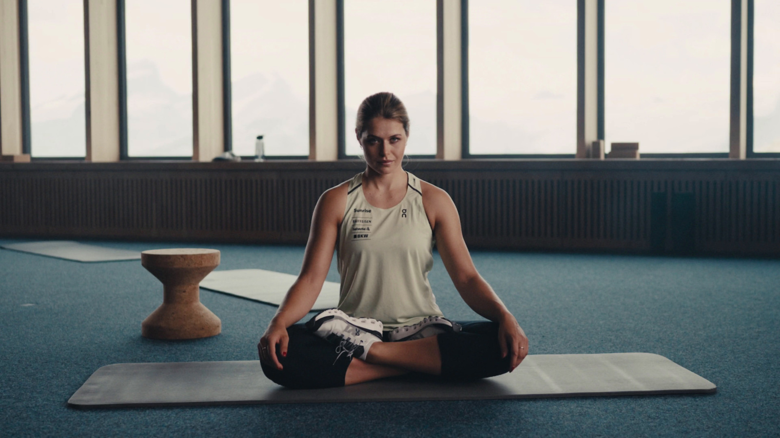 a woman sitting on a yoga mat in a room