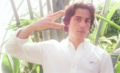 a man in a white shirt standing in front of a fence