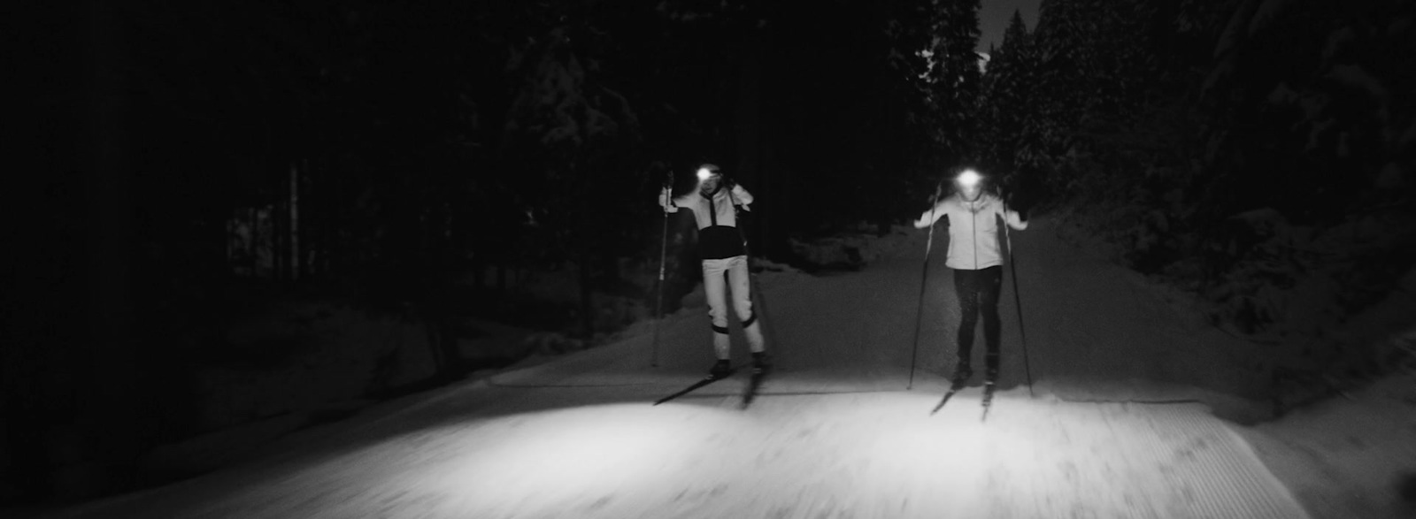 a couple of people riding skis down a snow covered slope