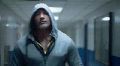 a man in a hooded sweatshirt walking down a hallway