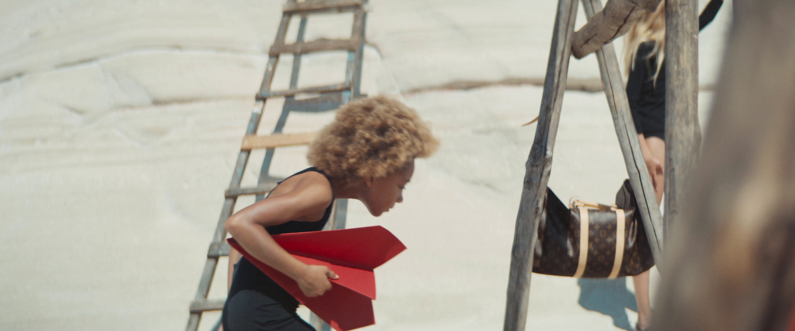 a woman holding a red folder while standing next to a ladder