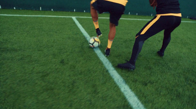 two men are kicking a soccer ball on a field