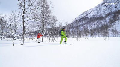 a couple of people riding skis down a snow covered slope