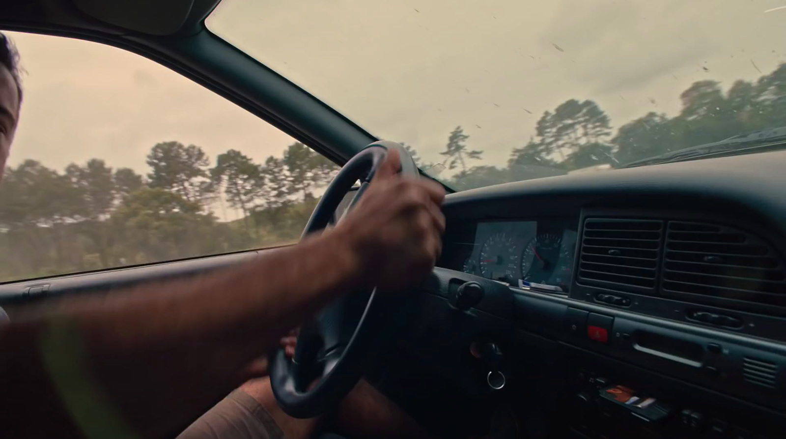 a man driving a car on a cloudy day