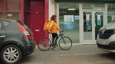 a woman riding a bike down a street next to parked cars