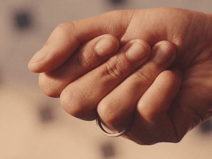 a close up of a person's hand holding a ring