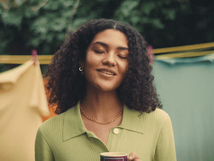 a woman with curly hair holding a cup of coffee