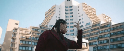 a woman with headphones is standing in front of a building