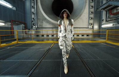 a woman in a white suit is running in a tunnel