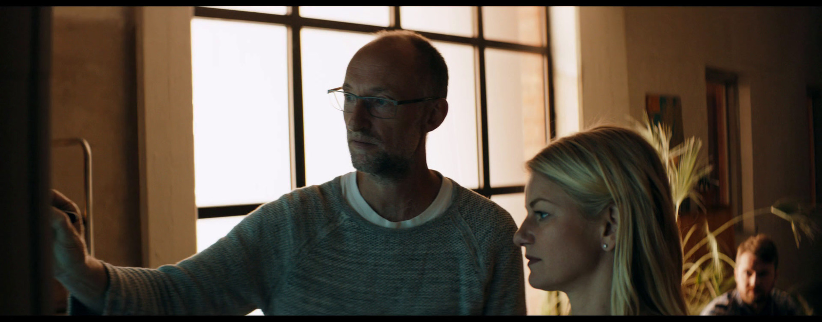 a man standing next to a woman in front of a window