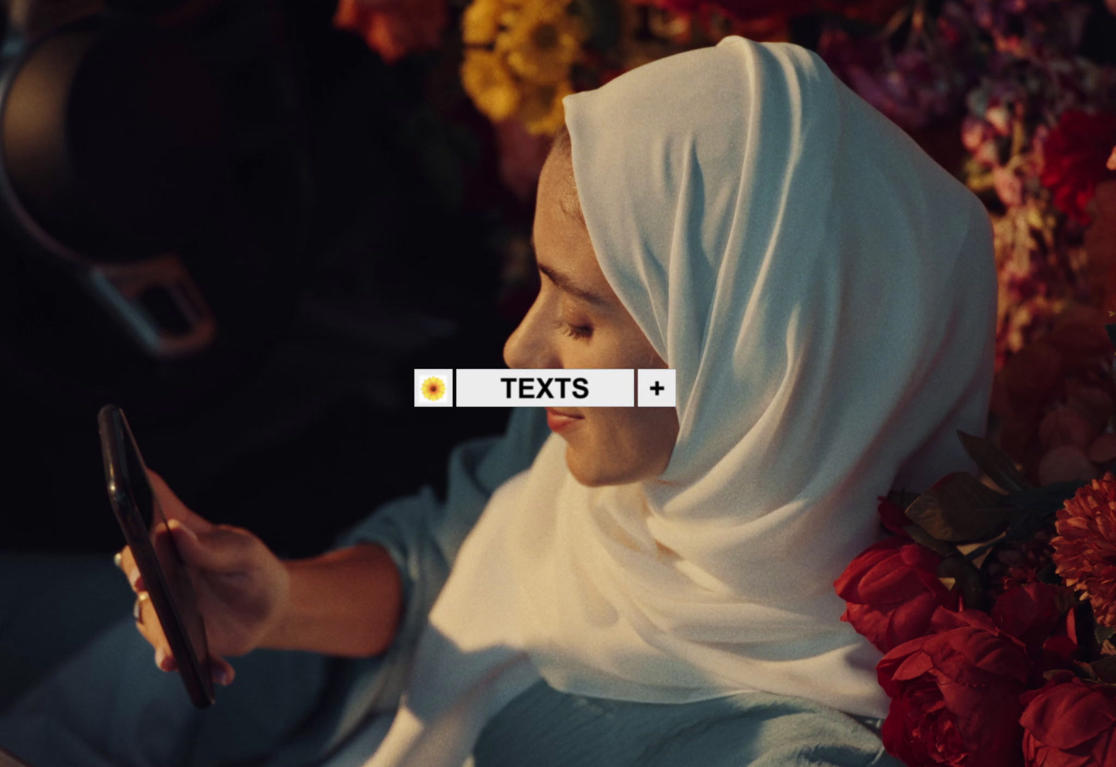 a woman in a headscarf texting on her phone