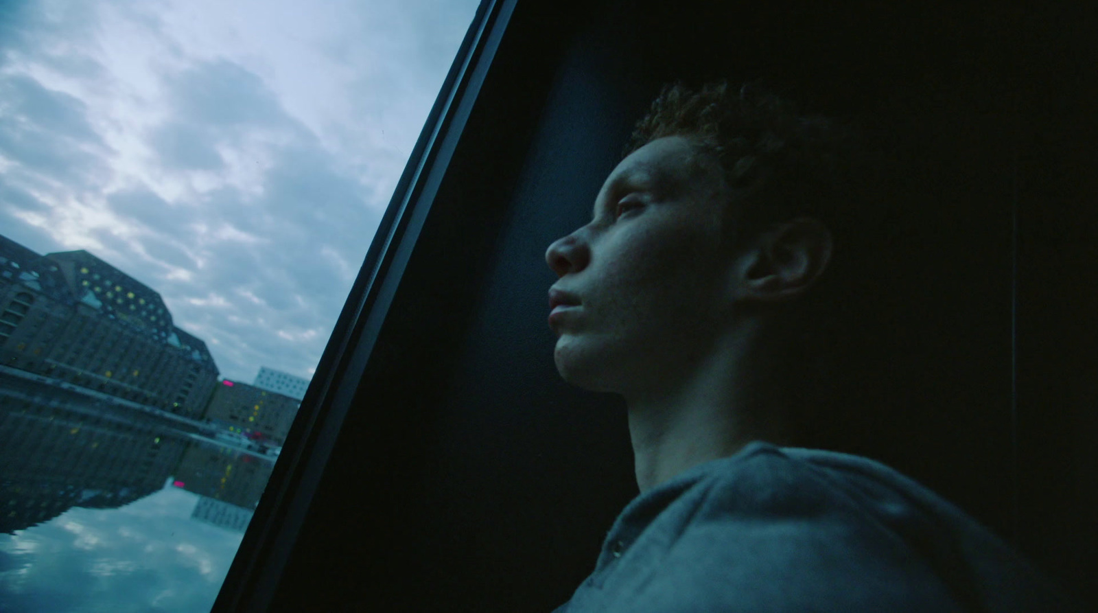 a man looking out a window at the sky