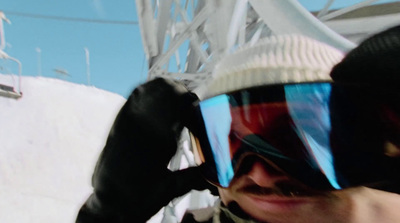 a man wearing goggles and a hat on top of a snow covered slope