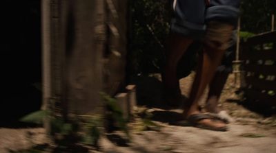 a man walking down a dirt road next to a fence