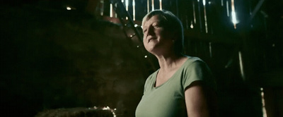 a woman in a green shirt standing in a dark room