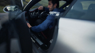 a man sitting in a car with his hand on the steering wheel