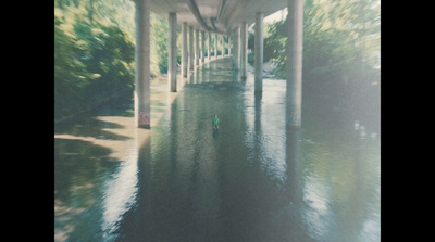 a person in a kayak on a river under a bridge