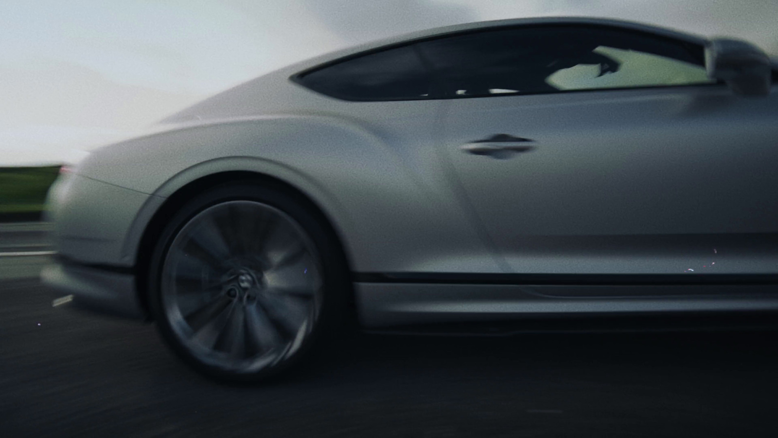 a silver sports car driving down a road